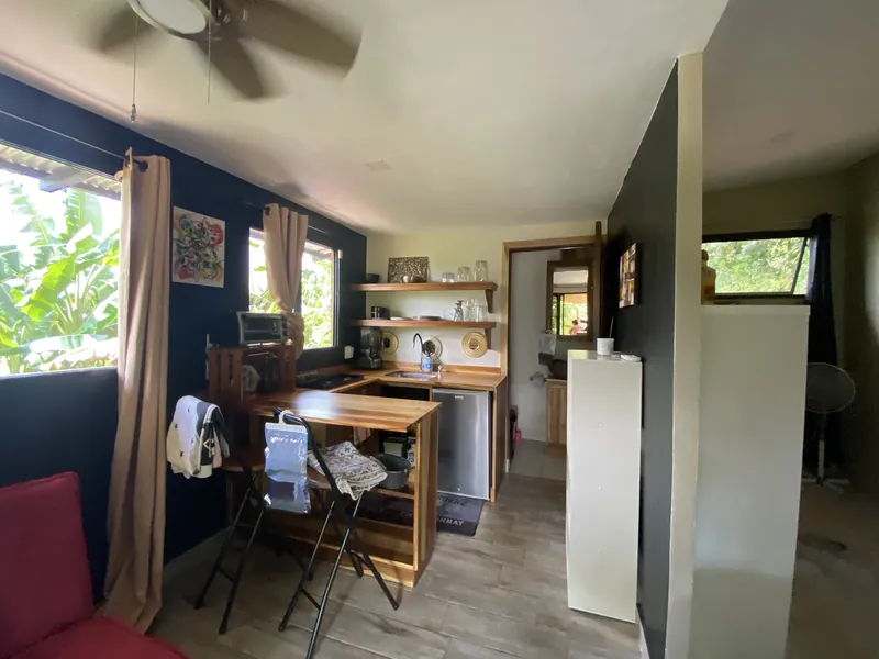 La kitchenette avec un bar en bois massif, des tabourets pliants, des étagères murales et un mur bleu marine.