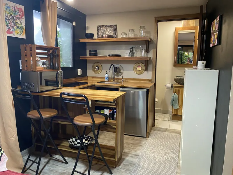 La kitchenette entièrement équipée avec un plan de travail en bois, un évier, un mini-réfrigérateur, un micro-ondes et deux tabourets de bar.