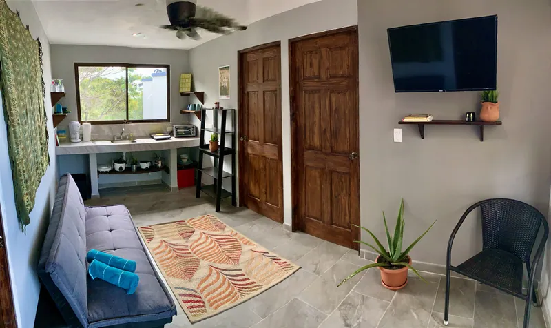 The living space at Villa Alegria, with a sofa, a kitchenette, and a wall-mounted television