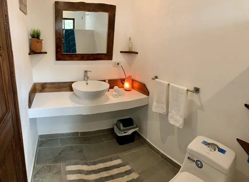 The bathroom at Villa Alegria, with a vessel sink on a wooden vanity and a framed mirror