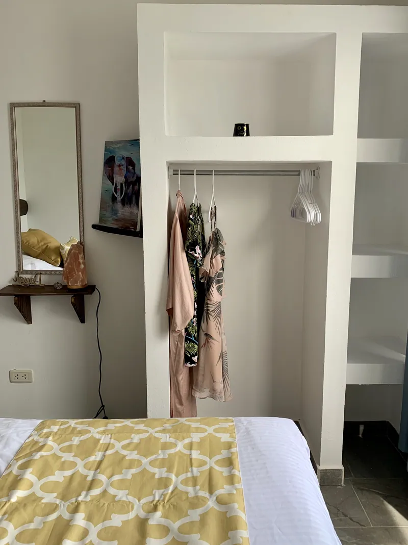 A bedroom at Villa Alegria with an open closet nook, a mirror, and a salt lamp