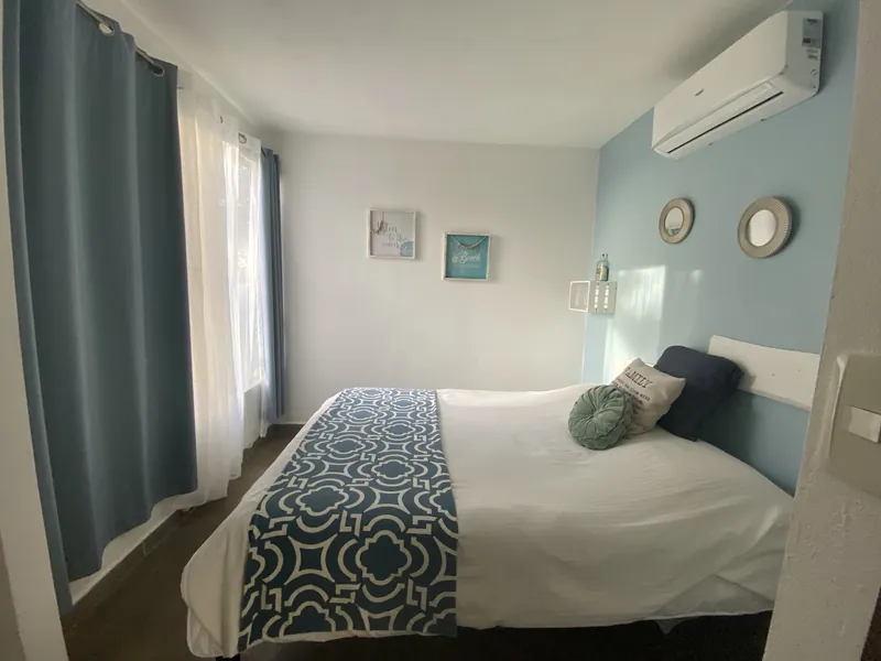The bedroom at Villa Luna, a bed against a soft blue accent wall beside a curtained window