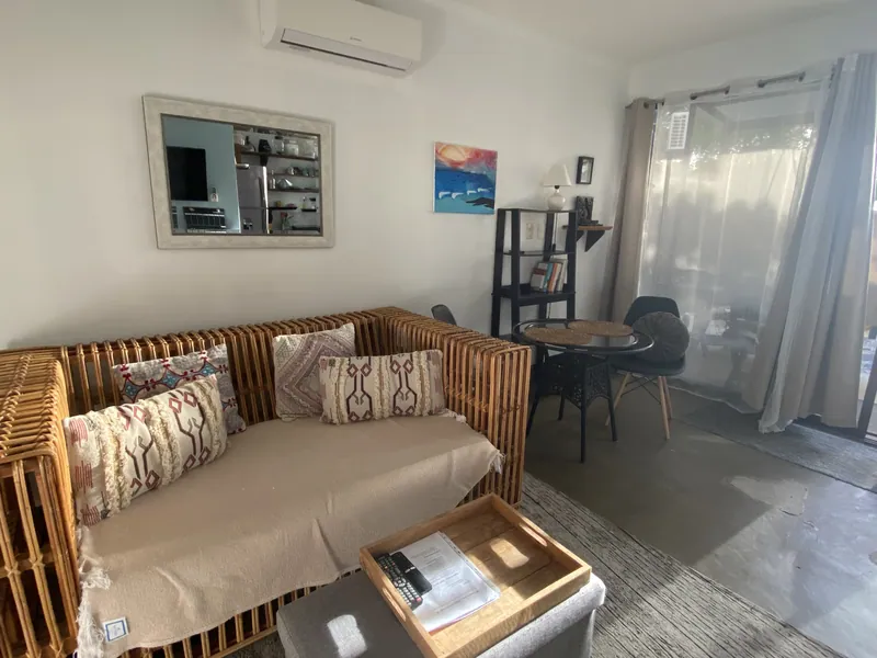 The living room seating at Villa Luna, a rattan sofa with patterned cushions beside a small dining table