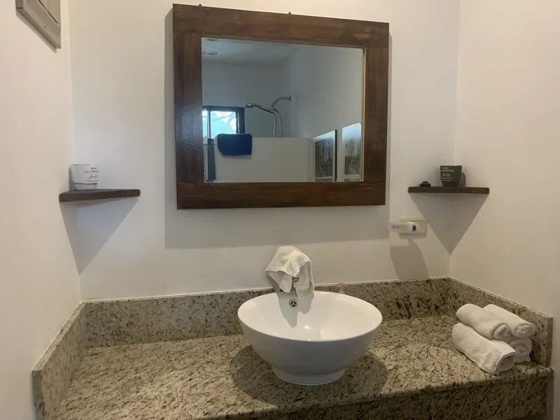 The bathroom vanity at Villa Luna, a white vessel sink on granite beneath a wood-framed mirror