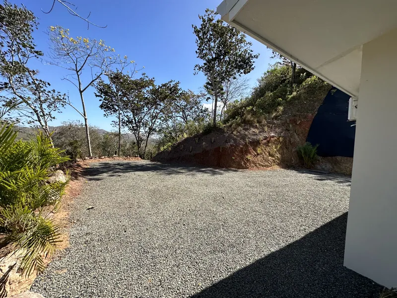 The gravel motor court beside Villa Lunax, framed by native trees and the hillside beyond