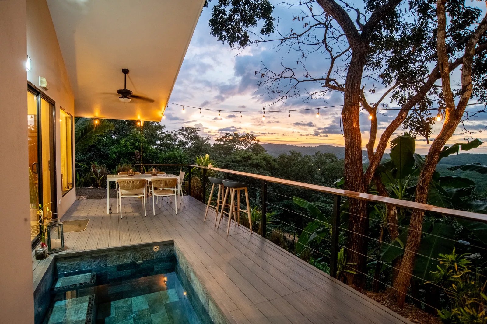 The covered deck at Villa Lunax at dusk, its plunge pool and dining table set above the jungle valley