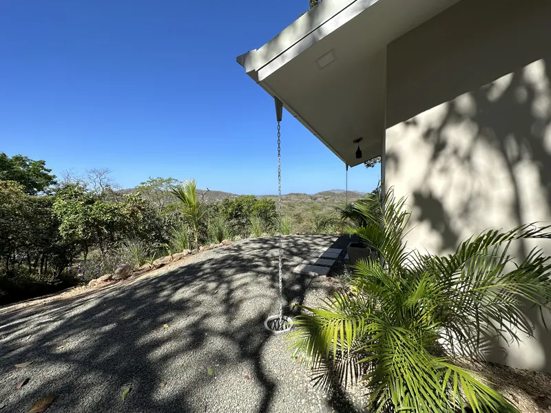 A shaded side path at Villa Lunax, palms in the foreground and the valley beyond