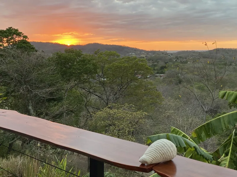 Sunset over the forested valley from the deck railing at Villa Lunax