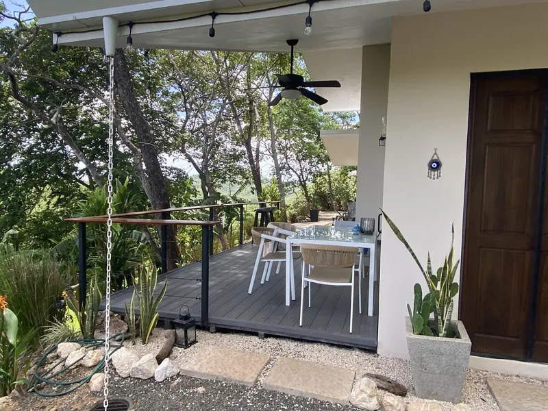 The covered outdoor dining deck at Villa Lunax, string lights and jungle all around