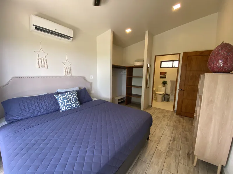 The first bedroom at Villa Lunax, king bed with a walk-in closet and ensuite bath beyond