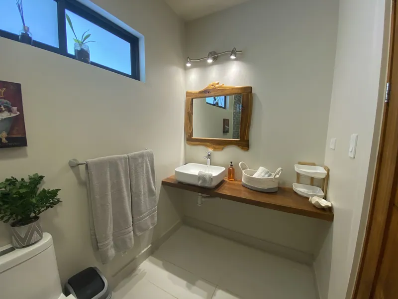 The first ensuite at Villa Lunax, a live-edge wood mirror above the vessel sink