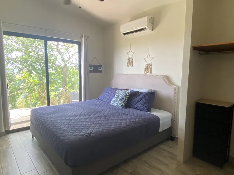 The first bedroom at Villa Lunax opening through sliding glass to the green terrace