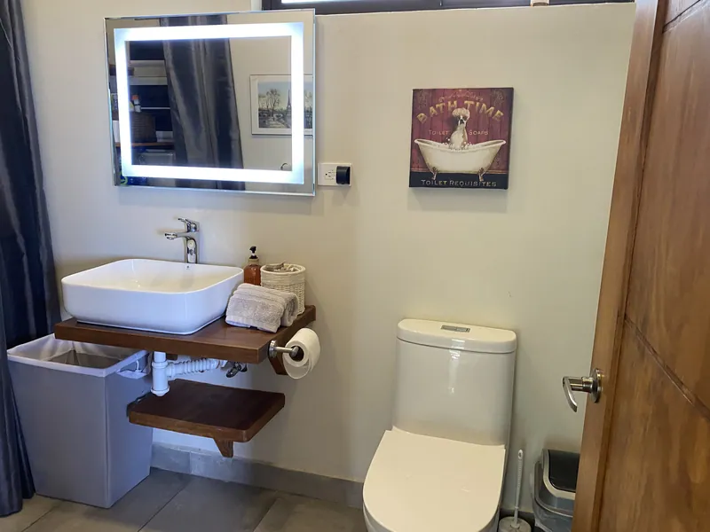 The second ensuite at Villa Lunax, a back-lit mirror above a floating wood vanity