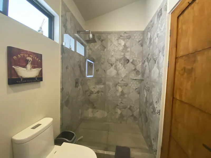 The walk-in shower with grey mosaic tile in the second bathroom at Villa Lunax