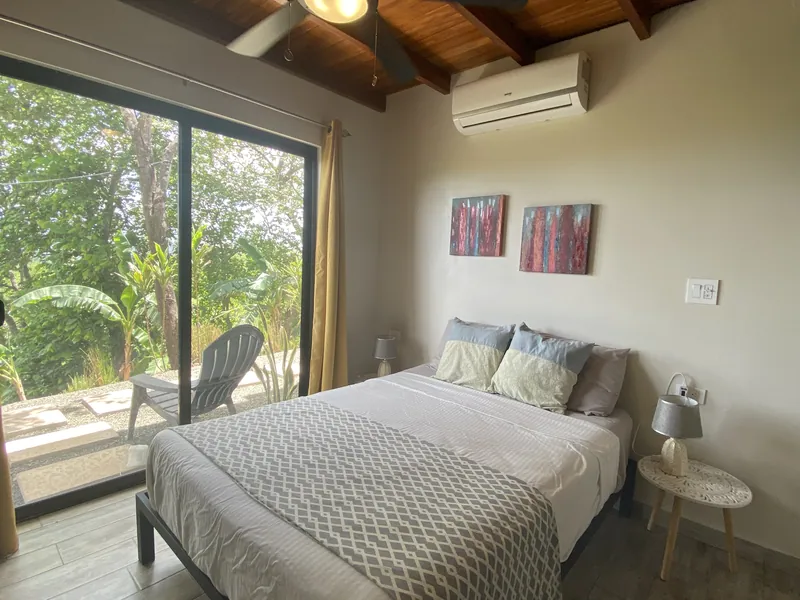 The second bedroom at Villa Lunax under a teak ceiling, sliding doors to a private terrace
