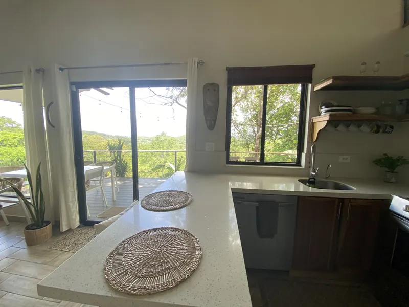 The kitchen counter at Villa Lunax beside sliding doors to the deck and jungle view