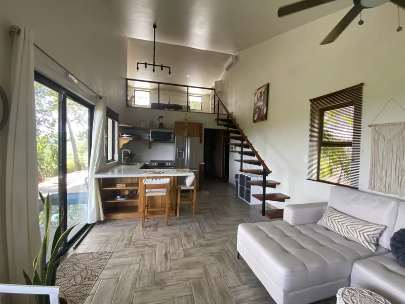 The open living and kitchen at Villa Lunax, a sectional sofa and the stair to the loft