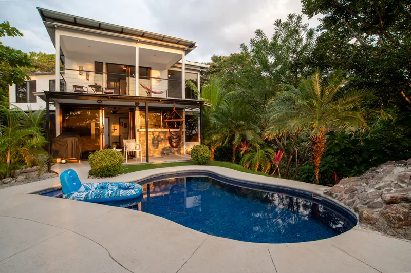 The two-storey Villa Sol and its curved blue pool in the garden at dusk