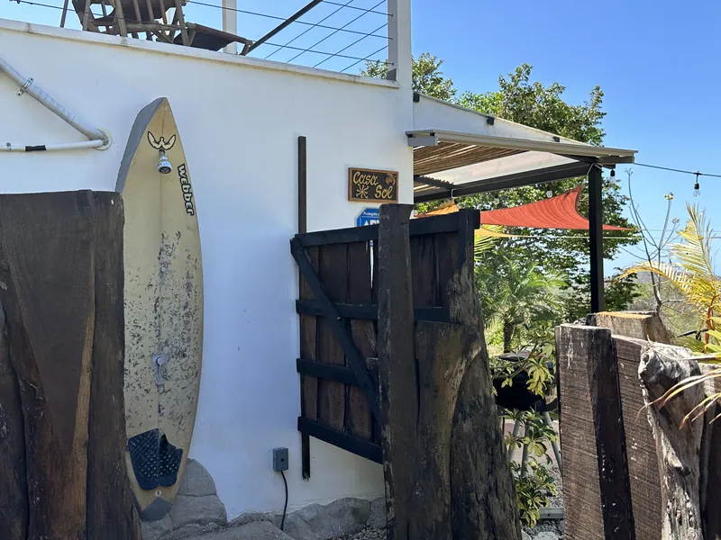 The carved "Casa Sol" sign and a surfboard by the villa's garden gate