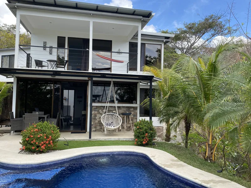 The Villa Sol facade with a balcony hammock and hanging chair above the pool