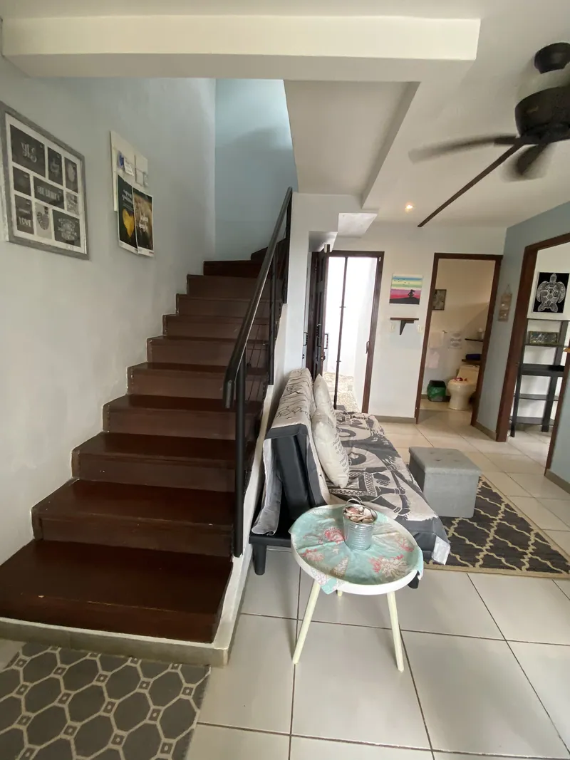 The open living room with its wooden staircase and sofa at Villa Sol
