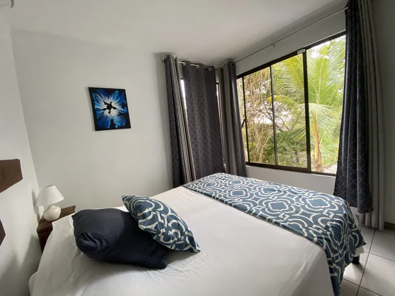 A ground-floor bedroom at Villa Sol with blue linens and a garden window