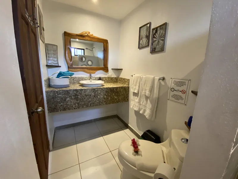 The main-floor bathroom vanity with a carved wood mirror and granite counter at Villa Sol