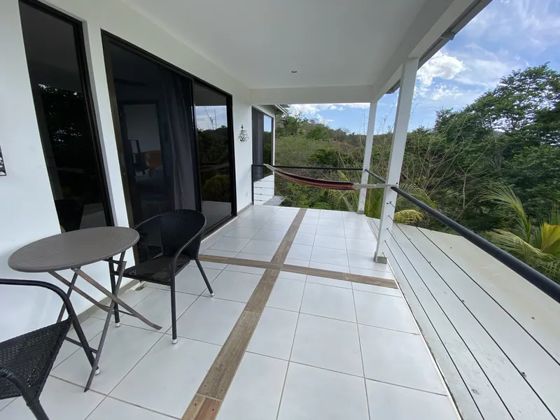 The upstairs balcony at Villa Sol with a hammock, table and jungle view