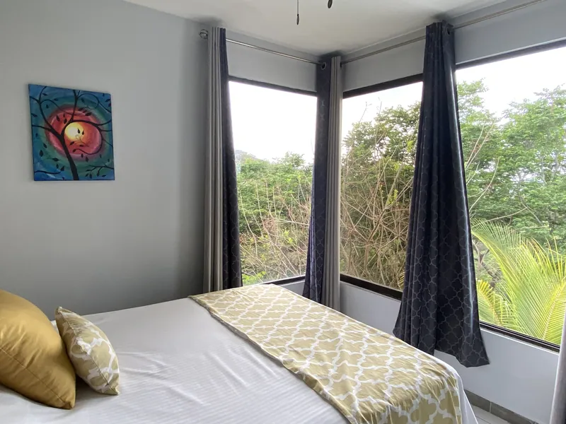 The upstairs bedroom at Villa Sol with corner windows and treetop views
