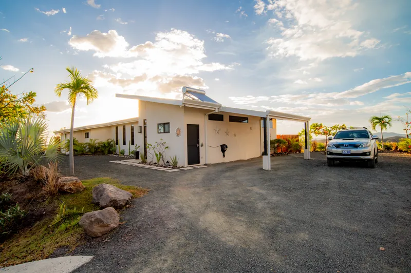 The clean-lined facade of Villa Toltec at golden hour, a palm and covered carport beside it