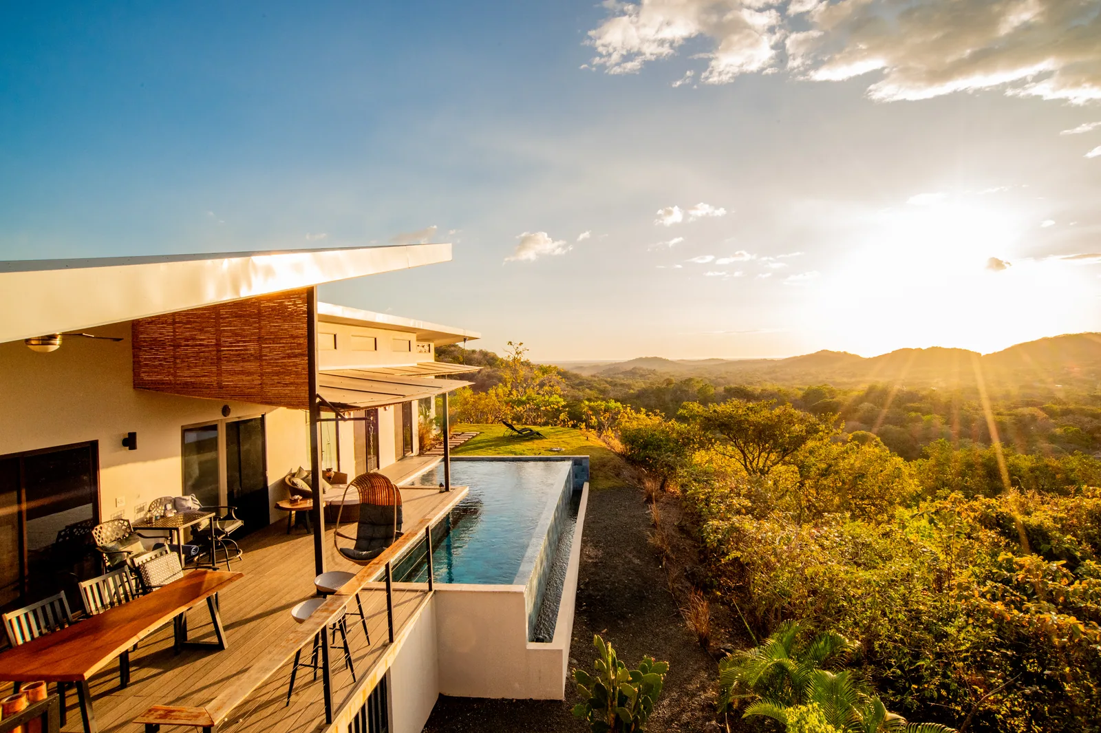 The deck, bar seating and infinity pool at Villa Toltec as the sun sets over the valley