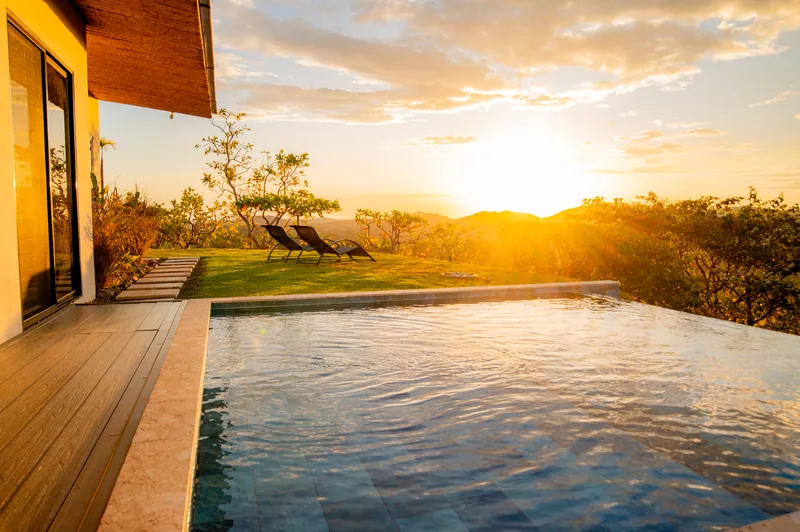 The infinity pool and sun loungers glowing in the low evening light