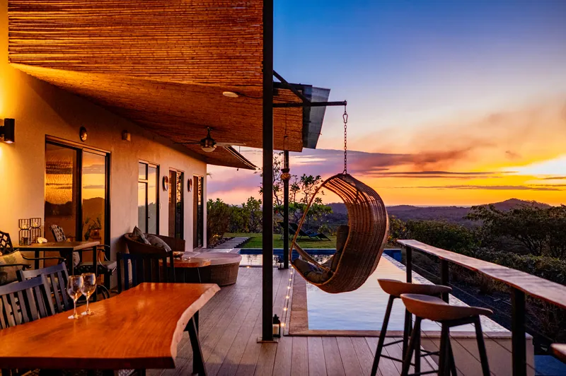The covered deck and hanging chair against a vivid orange sunset