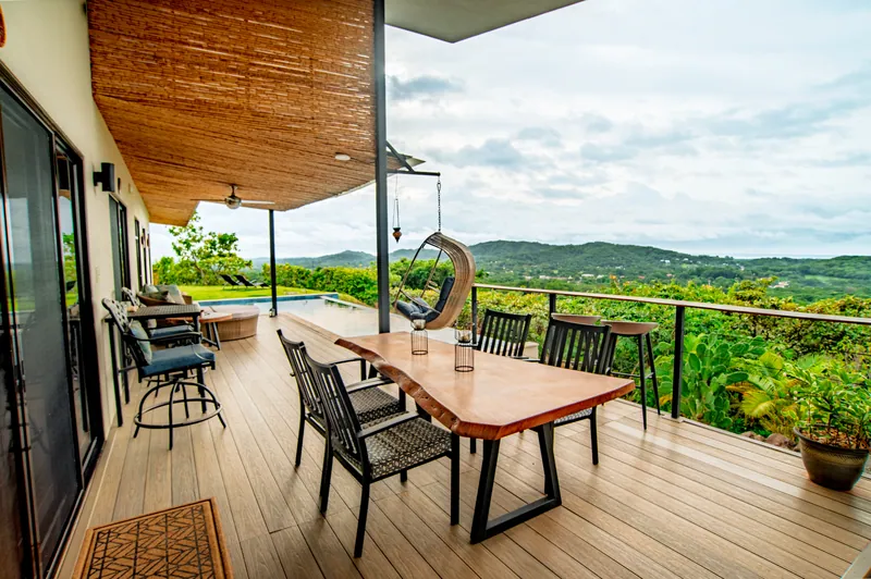 The outdoor dining table on the deck beneath the bamboo ceiling, valley beyond