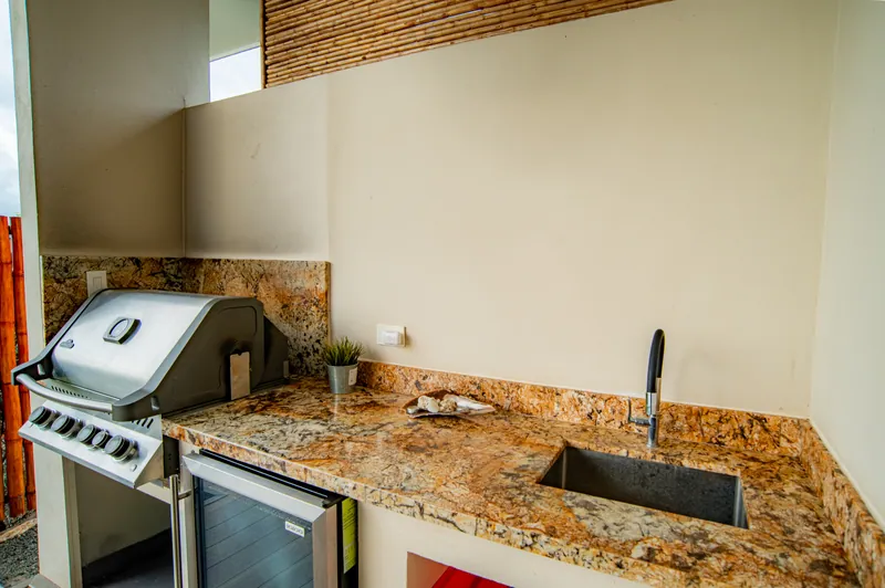 The outdoor kitchen with a gas grill and granite counter