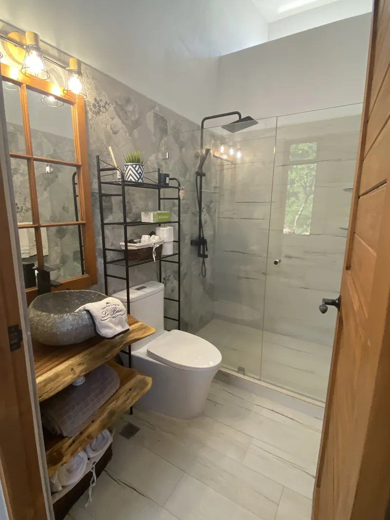 An interior bathroom with a stone vessel sink, walk-in glass shower and marble tile