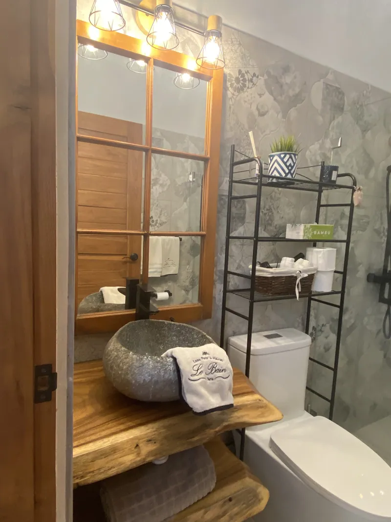 The stone basin and live-edge wood vanity of the interior bathroom, framed mirror above