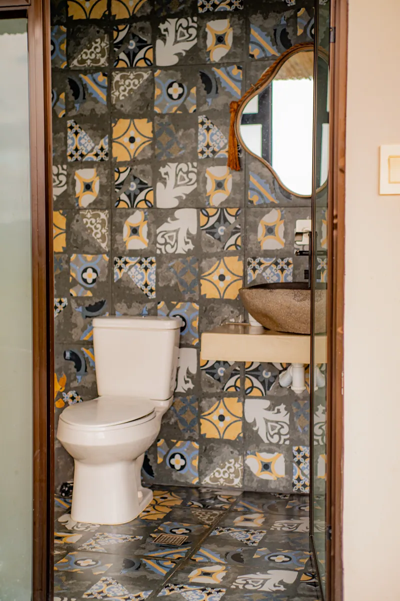 A powder room clad in patterned Moroccan-style tile with a stone vessel sink