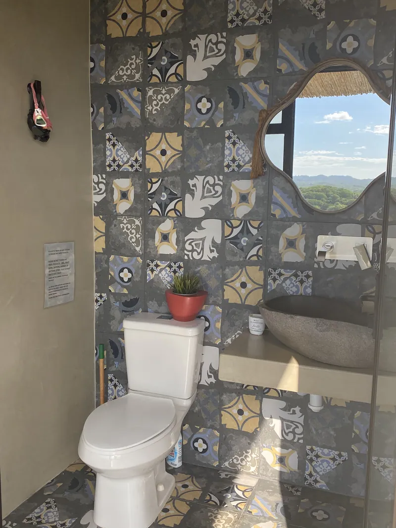 The patterned-tile bathroom, a shaped mirror framing the valley view
