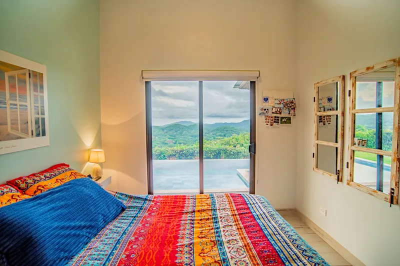 Sliding glass doors in the guest bedroom opening to the hills and infinity pool