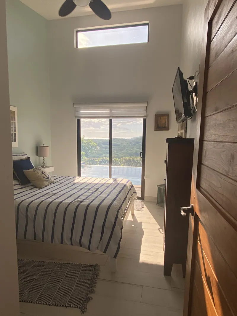 A guest bedroom with nautical striped bedding beneath a lofty ceiling