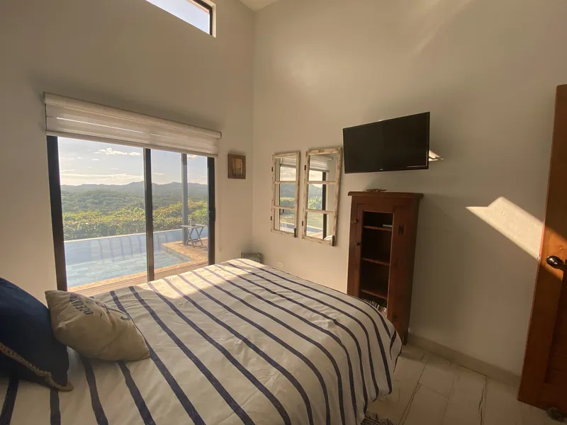 A second guest bedroom, striped linens and doors onto the pool terrace