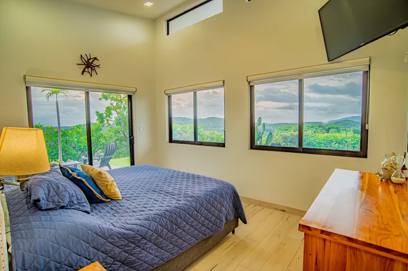 The master bedroom with a king bed and windows framing jungle and hills on every side