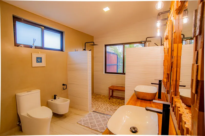 The master en-suite with double stone vessel sinks, a walk-in shower and warm wood