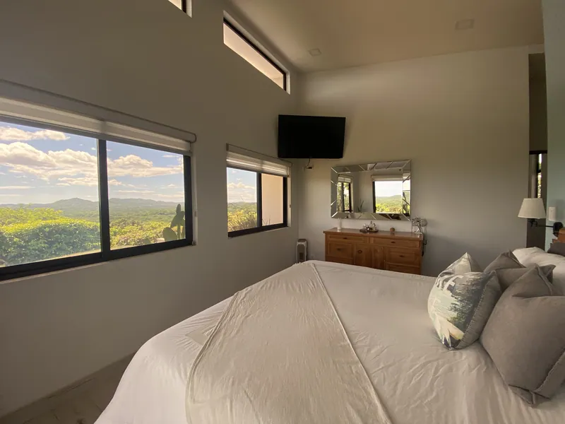 A wall of windows in the master bedroom over the treetops and distant mountains