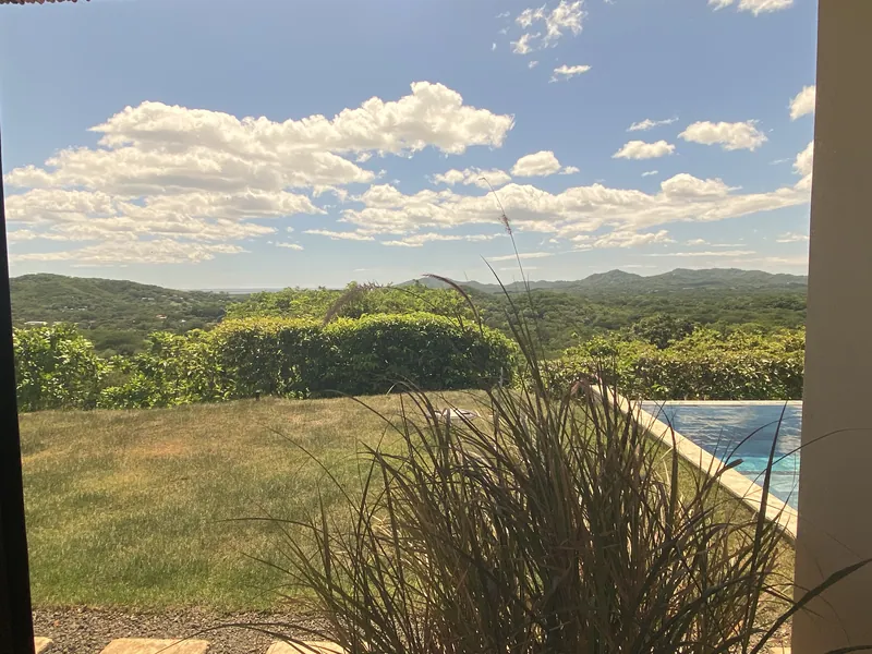 Green hills and a corner of the pool seen from the master bedroom deck