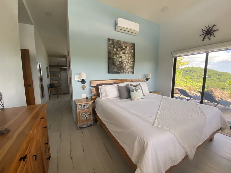 The spacious master suite opening onto the pool deck and hillside view