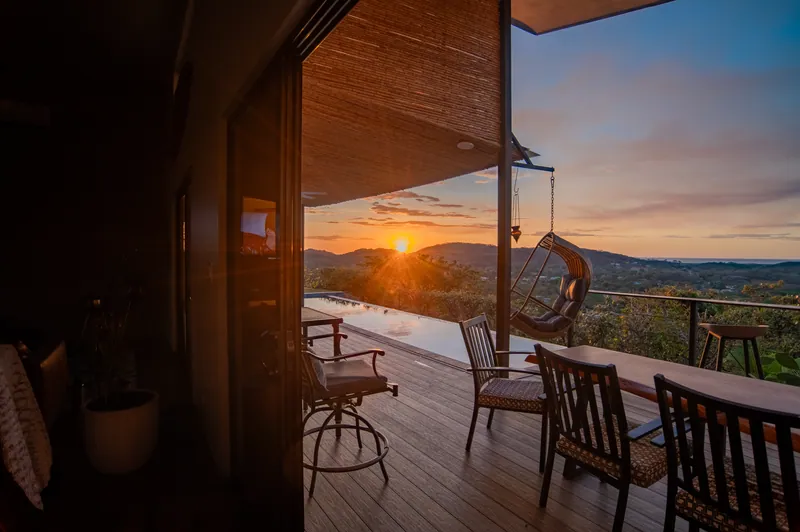 The covered deck and hanging chair at sunset, seen from inside Villa Toltec