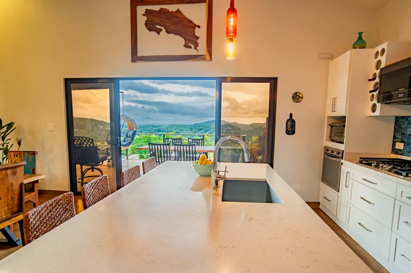 The kitchen island and sink framing the deck and hills through open glass doors