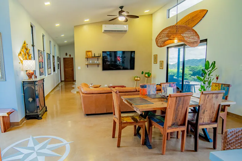 The open-plan living and dining room with a leather sofa and a gallery hallway